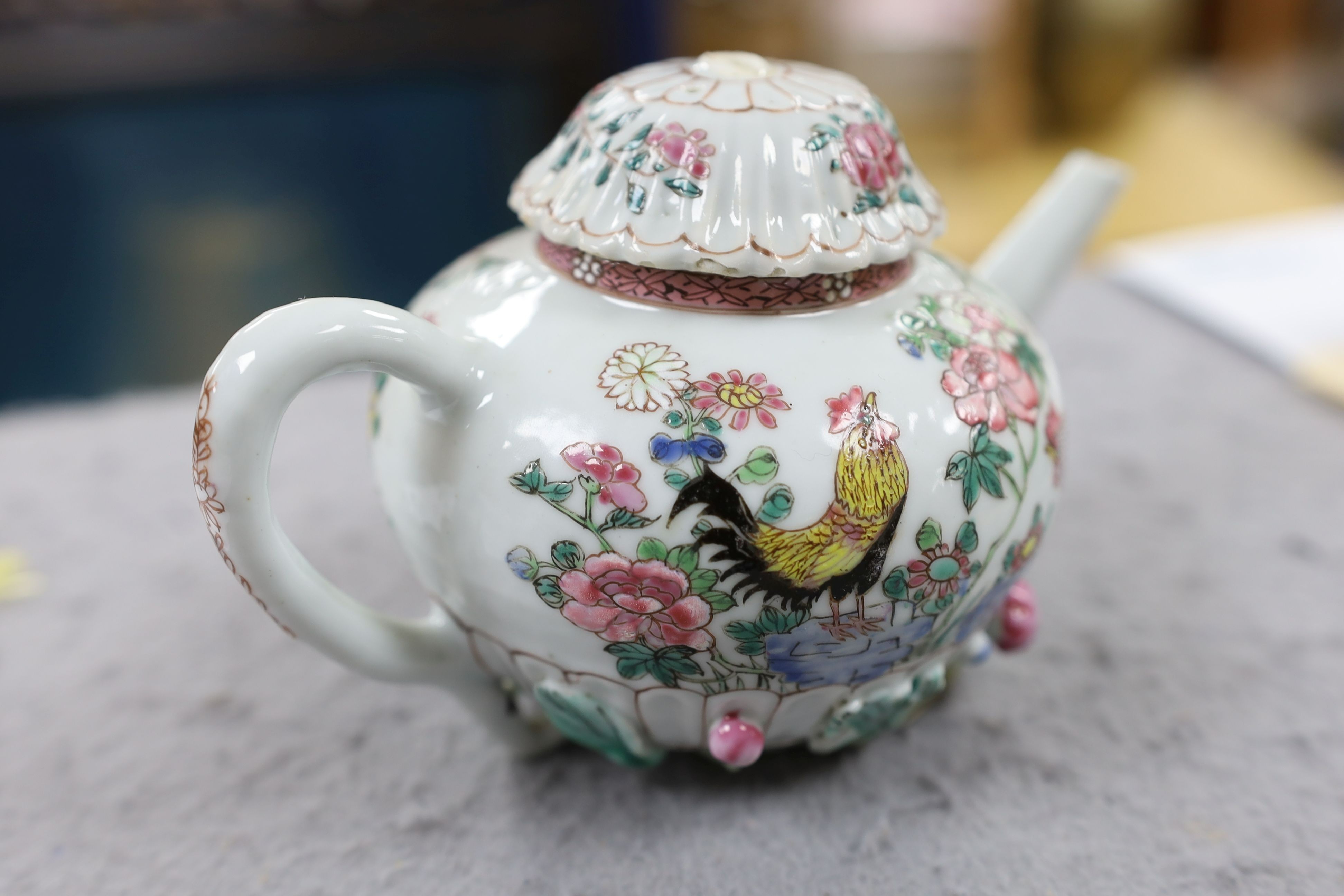 A Chinese famille rose chrysanthemum moulded teapot, early Qianlong period, painted with a cockerel amongst flowers, on a cage work base, 10 cms high